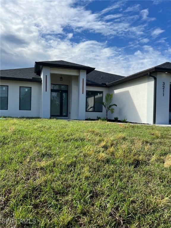 back of house featuring a yard and stucco siding