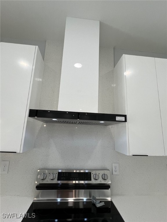 kitchen with modern cabinets, stainless steel electric stove, light countertops, wall chimney range hood, and white cabinetry