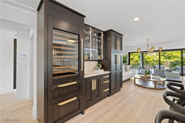 bar featuring light wood-style flooring, baseboards, a notable chandelier, and recessed lighting