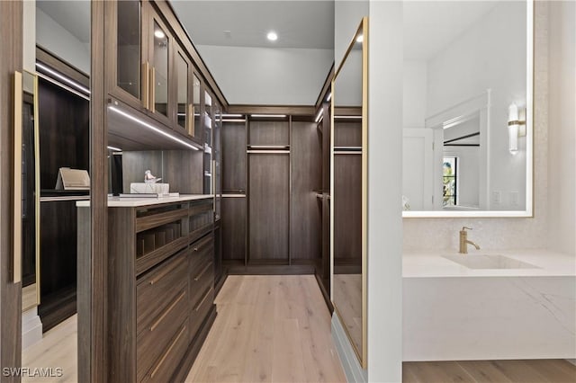 walk in closet featuring a sink and light wood finished floors