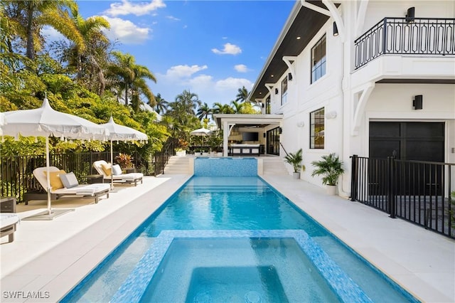 view of swimming pool with a patio area, a pool with connected hot tub, and fence