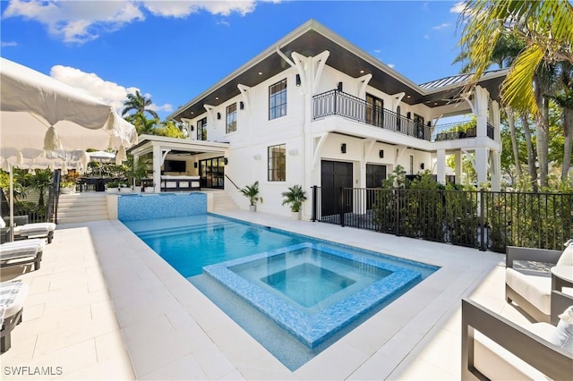 back of house with a patio, a pool with connected hot tub, an outdoor hangout area, fence, and a balcony