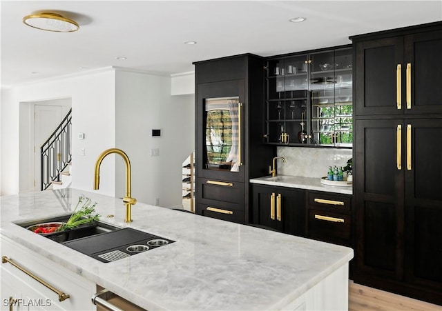 bar with decorative backsplash, wet bar, light wood-style floors, a sink, and recessed lighting