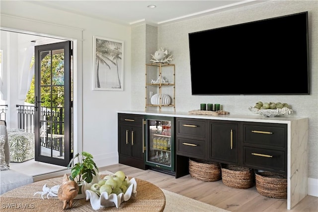 bar featuring a dry bar, light wood finished floors, beverage cooler, and baseboards