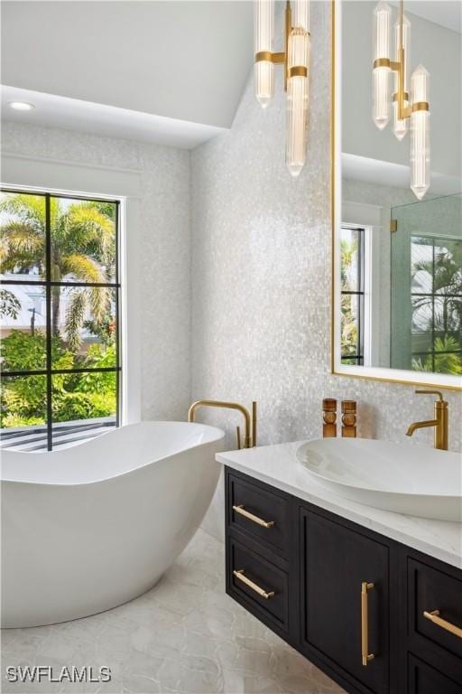 bathroom featuring marble finish floor, a soaking tub, and vanity