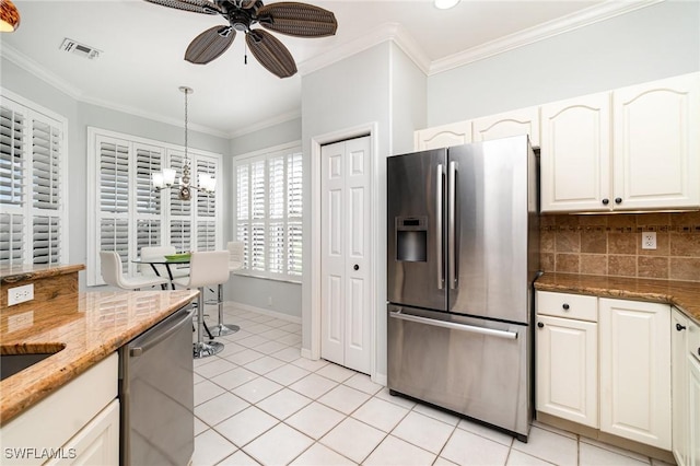 kitchen with light tile patterned floors, appliances with stainless steel finishes, ornamental molding, white cabinetry, and backsplash