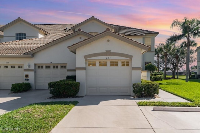 view of front of house featuring a tile roof, stucco siding, concrete driveway, a garage, and a front lawn