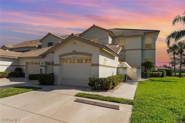 view of front facade with an attached garage, a tile roof, driveway, stucco siding, and a front yard