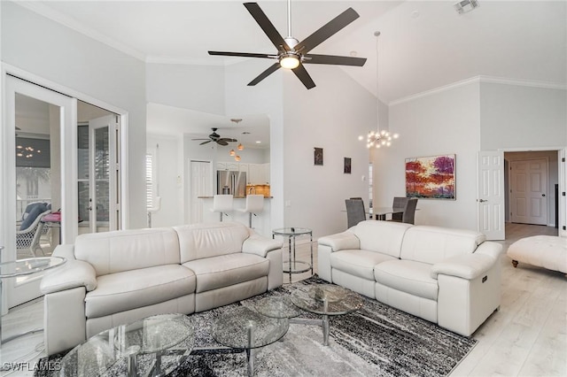 living room featuring high vaulted ceiling, ceiling fan with notable chandelier, visible vents, light wood-style floors, and ornamental molding