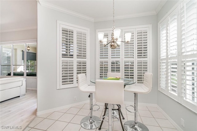 tiled dining space featuring baseboards, ornamental molding, a chandelier, and a wealth of natural light