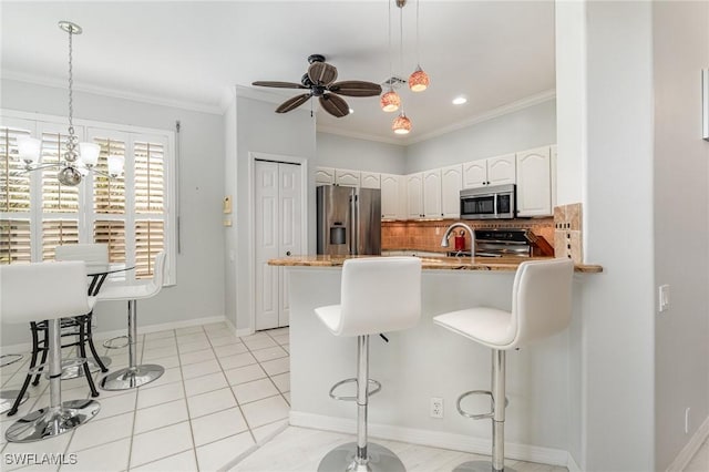 kitchen with appliances with stainless steel finishes, a kitchen breakfast bar, ornamental molding, a peninsula, and backsplash