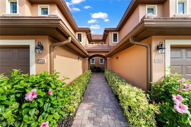 doorway to property featuring a garage and stucco siding