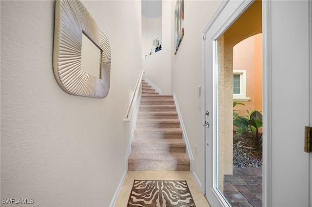 stairway featuring arched walkways and baseboards