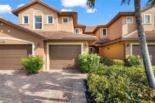 view of front of house with a tiled roof, decorative driveway, and stucco siding