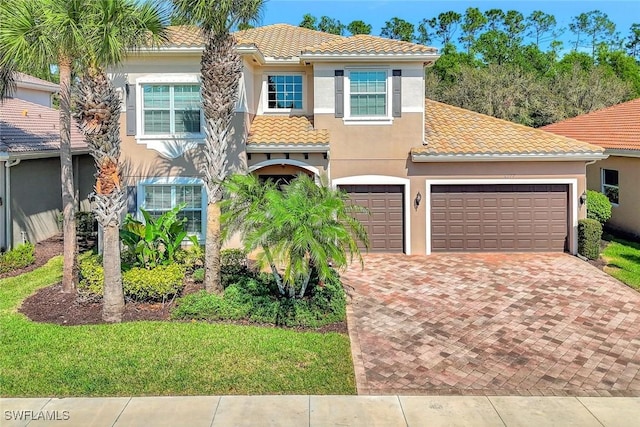 mediterranean / spanish-style house with decorative driveway, a tile roof, and stucco siding