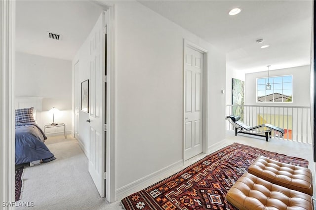 hallway featuring light colored carpet, visible vents, baseboards, and recessed lighting