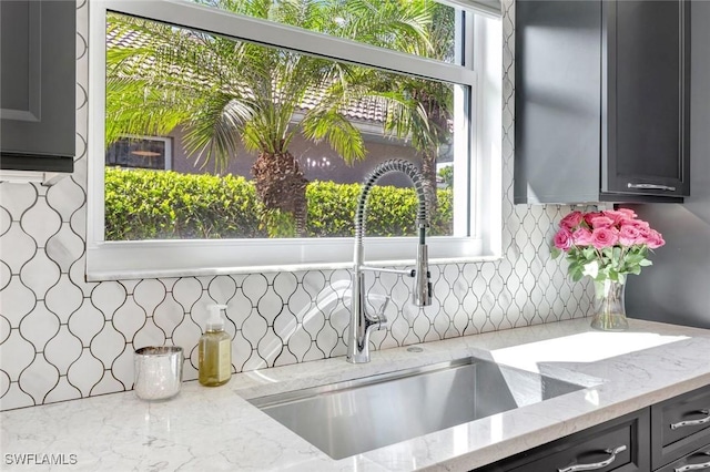 kitchen featuring backsplash, a sink, and light stone counters