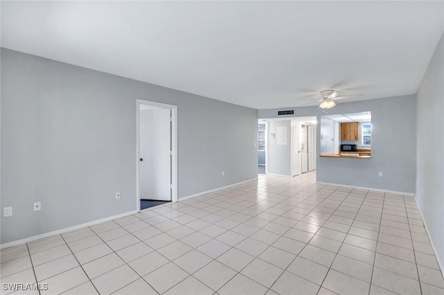 spare room with light tile patterned floors, baseboards, visible vents, and a ceiling fan