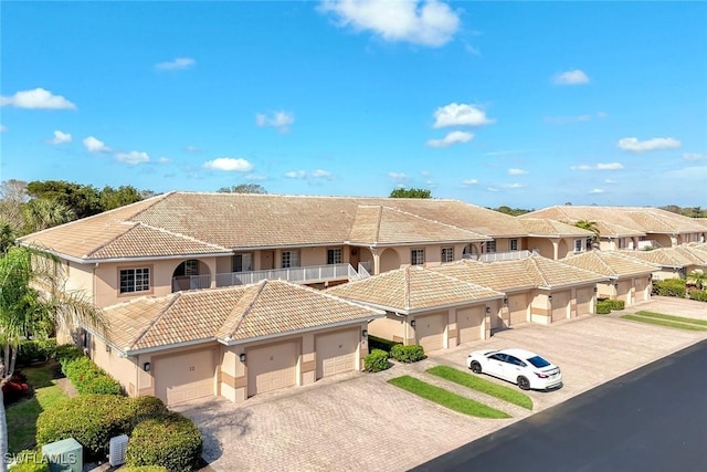 view of front of home with a garage, a tiled roof, decorative driveway, a residential view, and stucco siding