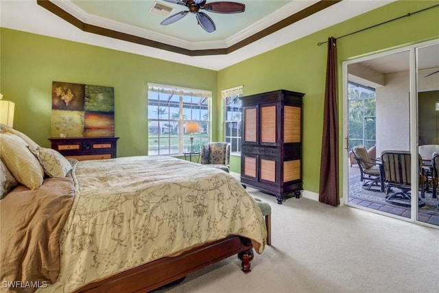 carpeted bedroom featuring access to outside, ornamental molding, multiple windows, and a raised ceiling