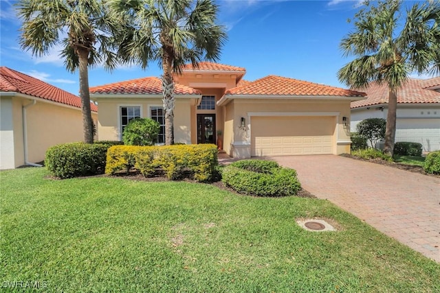 mediterranean / spanish-style house featuring a garage, a front lawn, decorative driveway, and stucco siding