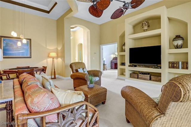 living area with arched walkways, carpet flooring, a ceiling fan, baseboards, and built in features