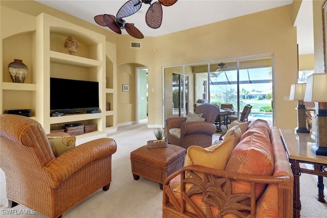 living room featuring ceiling fan, arched walkways, light carpet, visible vents, and built in features