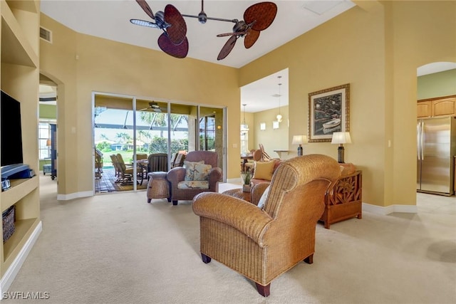 living room with visible vents, arched walkways, baseboards, light colored carpet, and ceiling fan