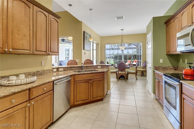 kitchen featuring light tile patterned floors, visible vents, hanging light fixtures, stainless steel appliances, and a sink