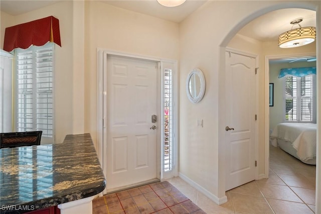 entrance foyer featuring light tile patterned floors, arched walkways, and baseboards