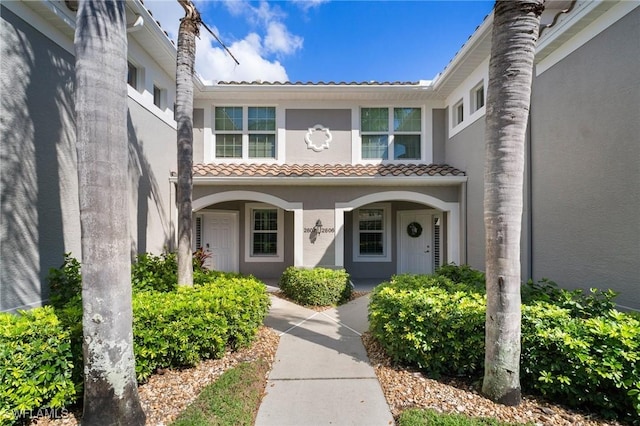 property entrance with covered porch, a tile roof, and stucco siding