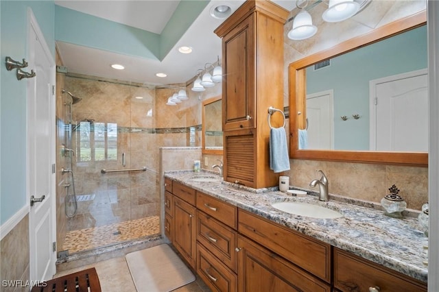 bathroom with double vanity, a sink, visible vents, and a shower stall