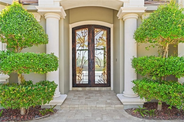 view of exterior entry featuring french doors and stucco siding