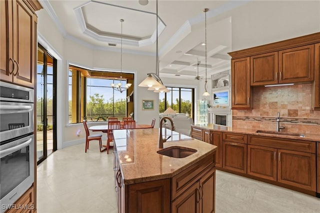 kitchen with a sink, light stone countertops, double oven, and crown molding