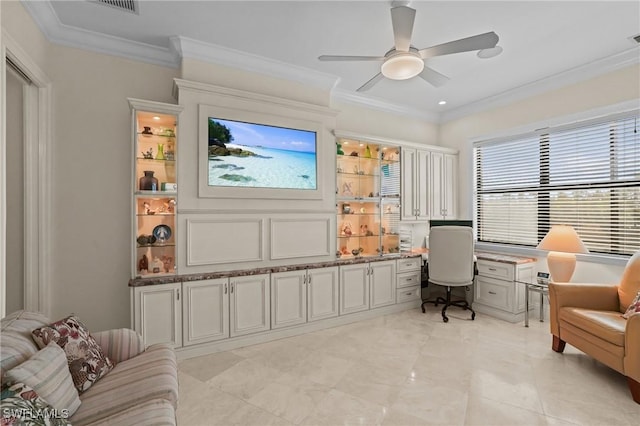 sitting room with built in desk, ceiling fan, and crown molding