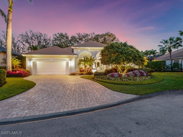 mediterranean / spanish home with a garage, decorative driveway, a front yard, and a tile roof