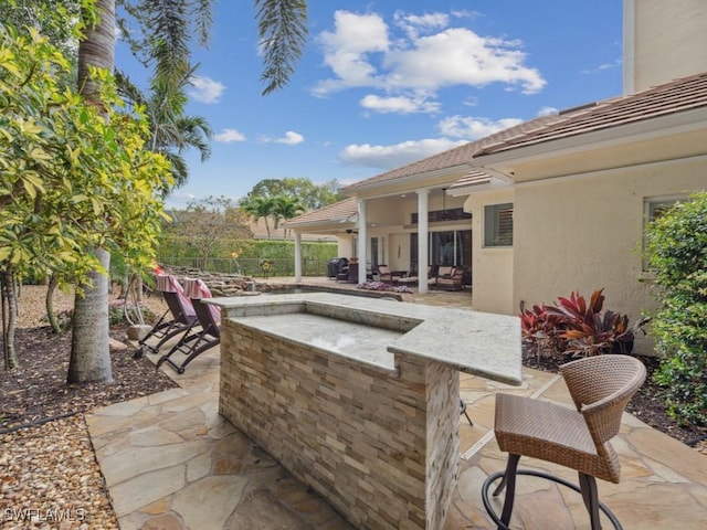 view of patio / terrace with exterior kitchen, fence, and outdoor dry bar