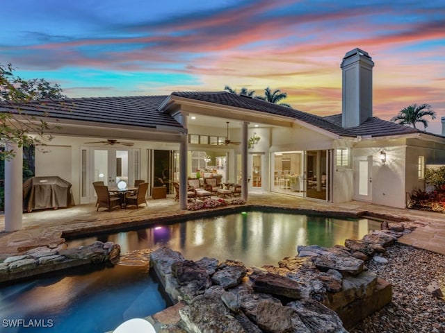 back of house with a patio, stucco siding, a ceiling fan, an outdoor pool, and a tiled roof