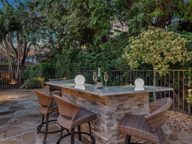 view of patio with outdoor dry bar and fence