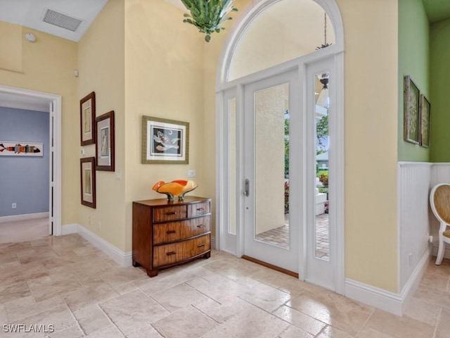 foyer entrance with a towering ceiling, baseboards, visible vents, and stone tile flooring