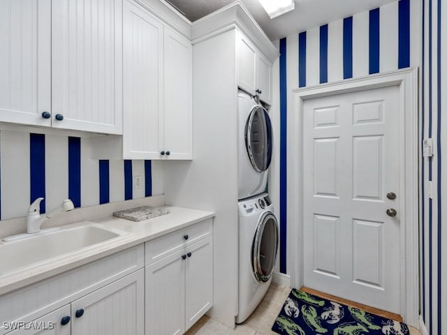 washroom with light tile patterned floors, stacked washer / dryer, a sink, and cabinet space