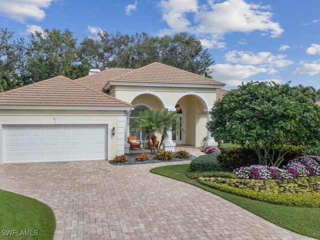 mediterranean / spanish house featuring a garage, decorative driveway, and stucco siding