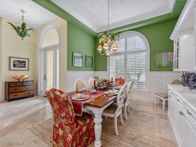 dining space featuring a chandelier, ornamental molding, and wainscoting