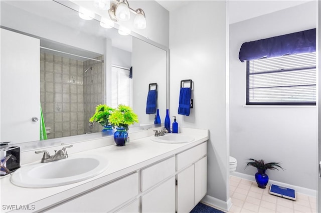 bathroom with baseboards, a sink, toilet, and double vanity