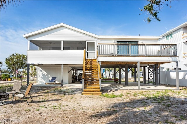 back of property featuring a carport, stairway, fence, and a sunroom