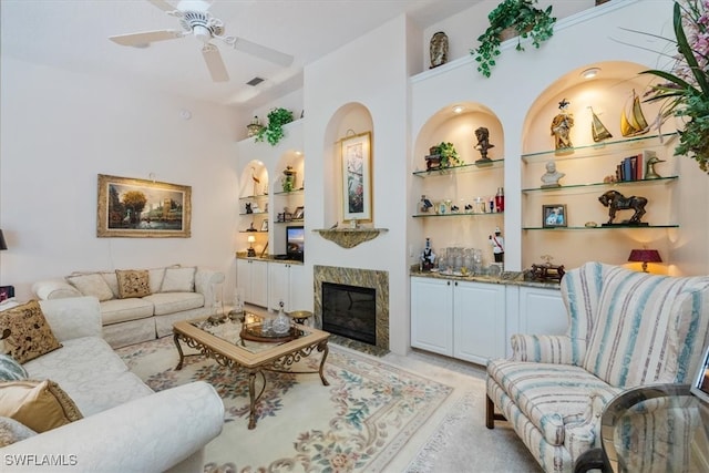 living room with visible vents, a ceiling fan, a high end fireplace, and built in features