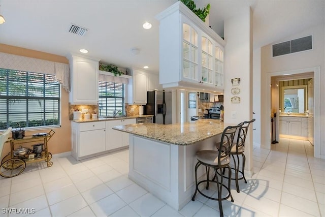 kitchen featuring a peninsula, visible vents, appliances with stainless steel finishes, and glass insert cabinets