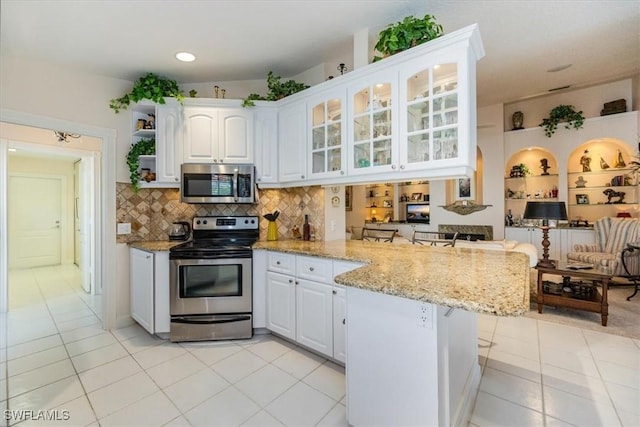 kitchen featuring stainless steel appliances, backsplash, glass insert cabinets, white cabinets, and a peninsula