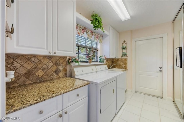 washroom with separate washer and dryer, light tile patterned flooring, a sink, and cabinet space