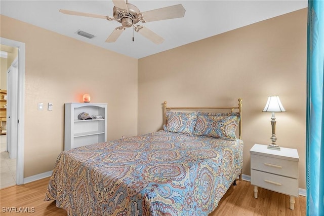 bedroom with light wood finished floors, visible vents, baseboards, and ceiling fan